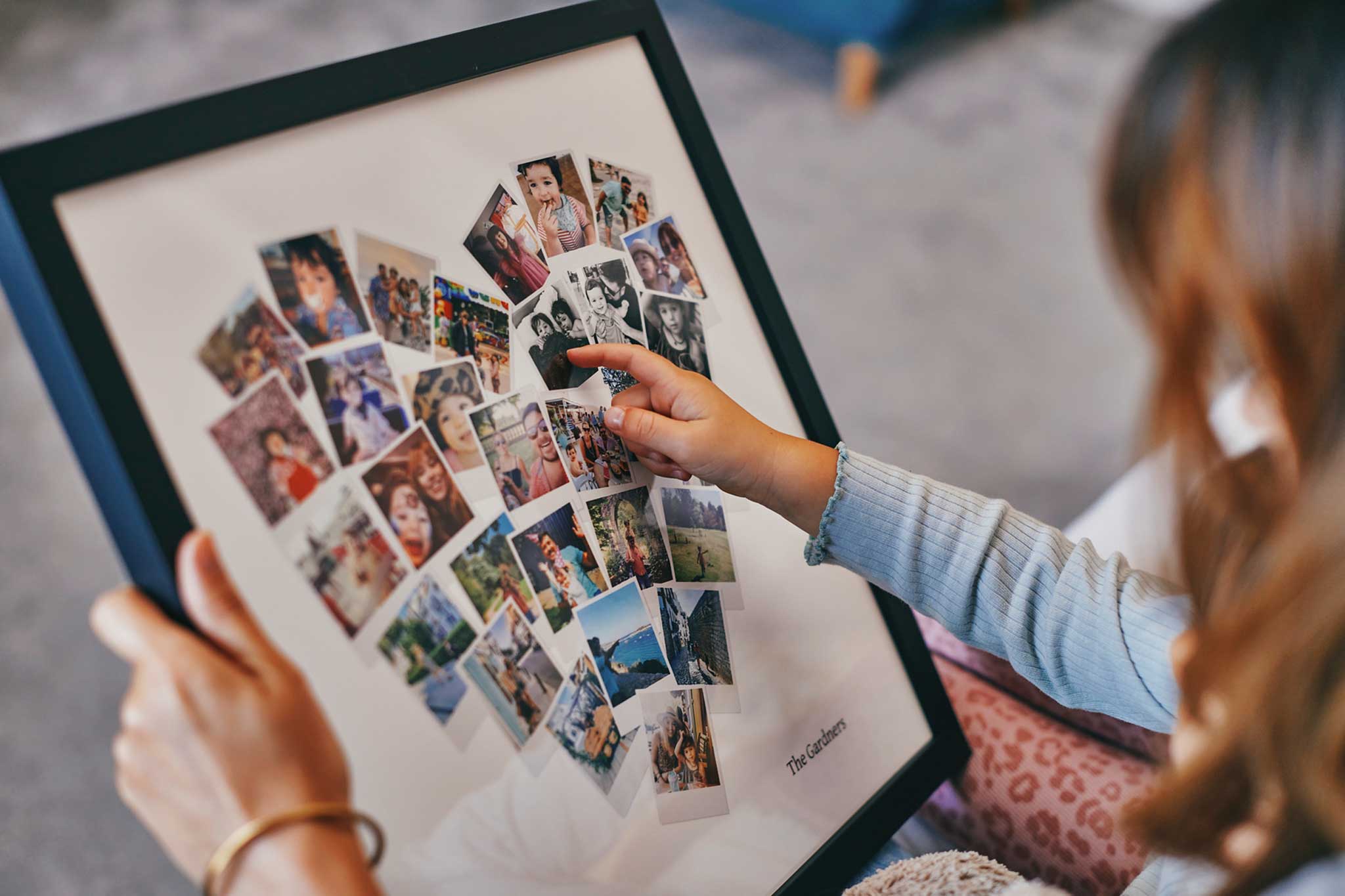 Een houten fotolijst met dertig foto's in een hartvormige collage