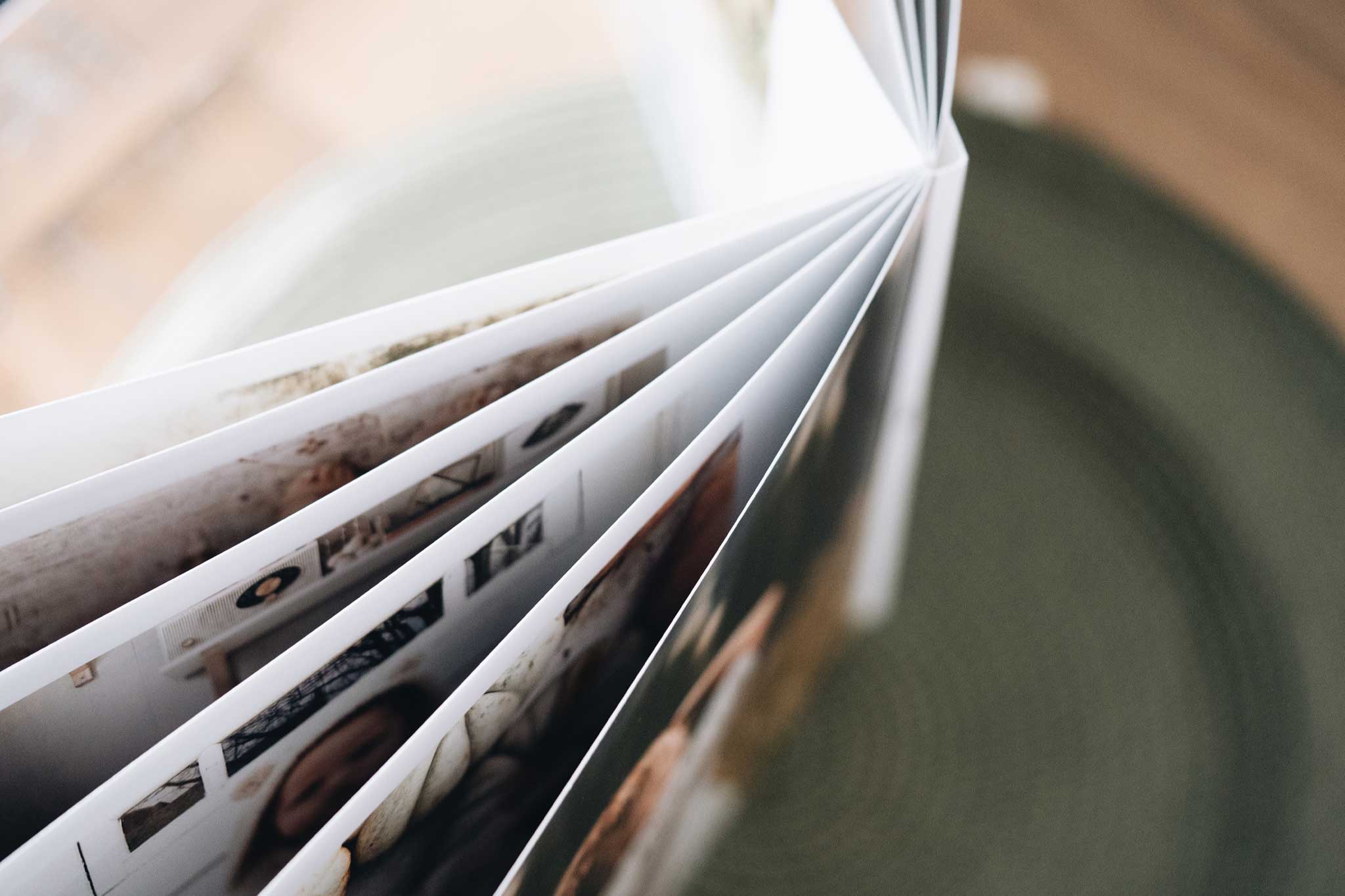 Handen die een open lay-flat fotoboek vasthouden met een naadloze spread in het midden
